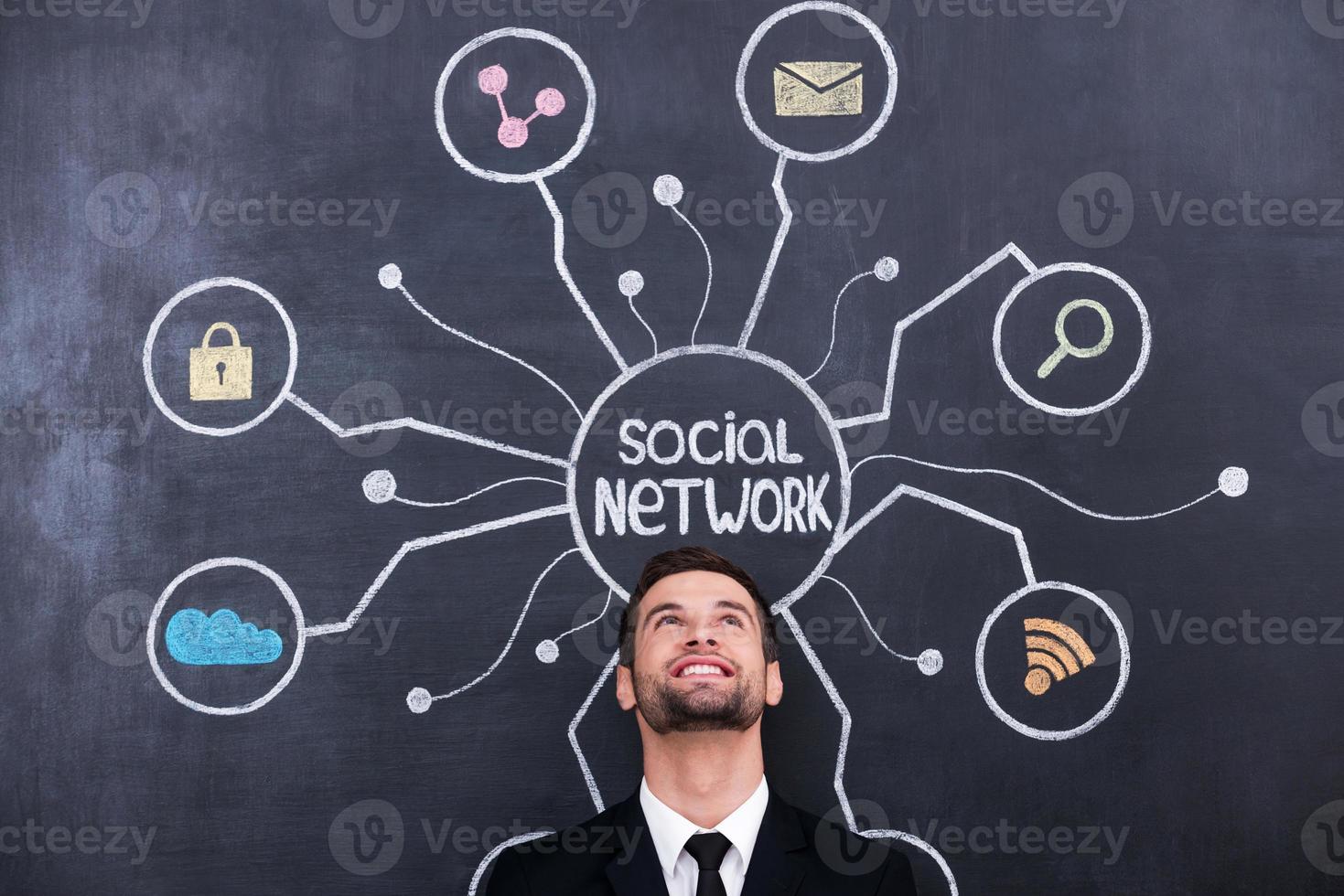 Such a wonderful world of internet. Handsome young man standing under social network chalk drawing on blackboard photo