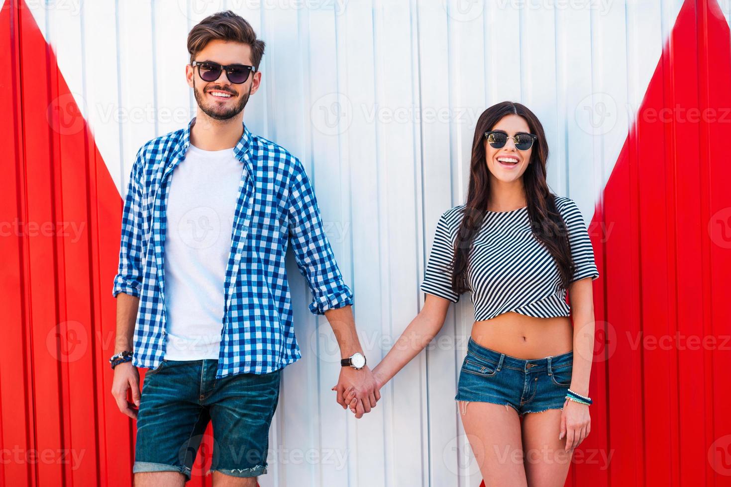 Young and in love. Smiling young loving couple holding hands and looking at camera while standing outdoors photo
