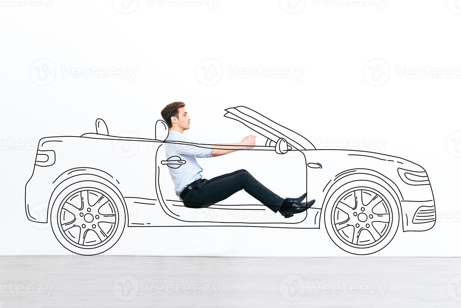 Going far away Handsome young man driving drawn car against white background photo