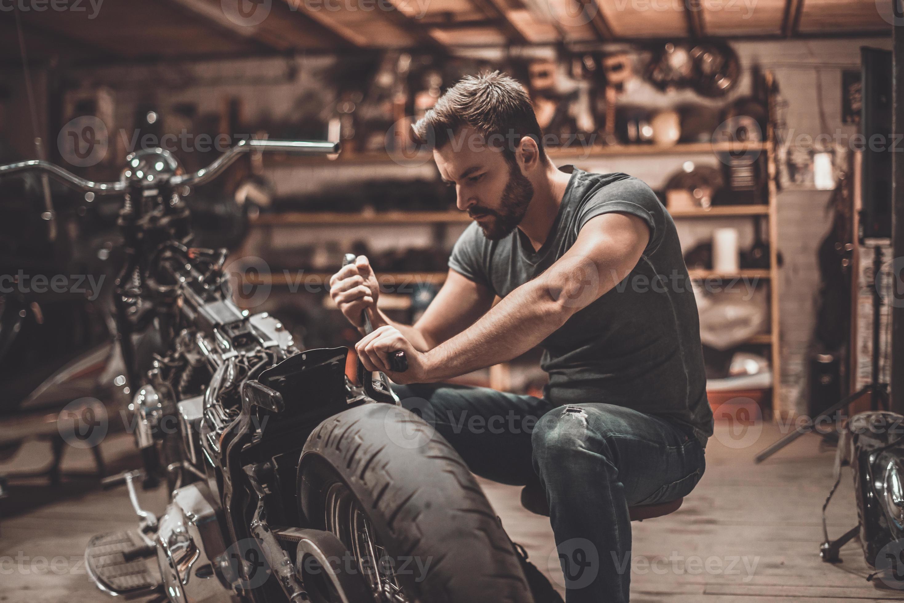 This bike will be perfect. Confident young man repairing motorcycle in