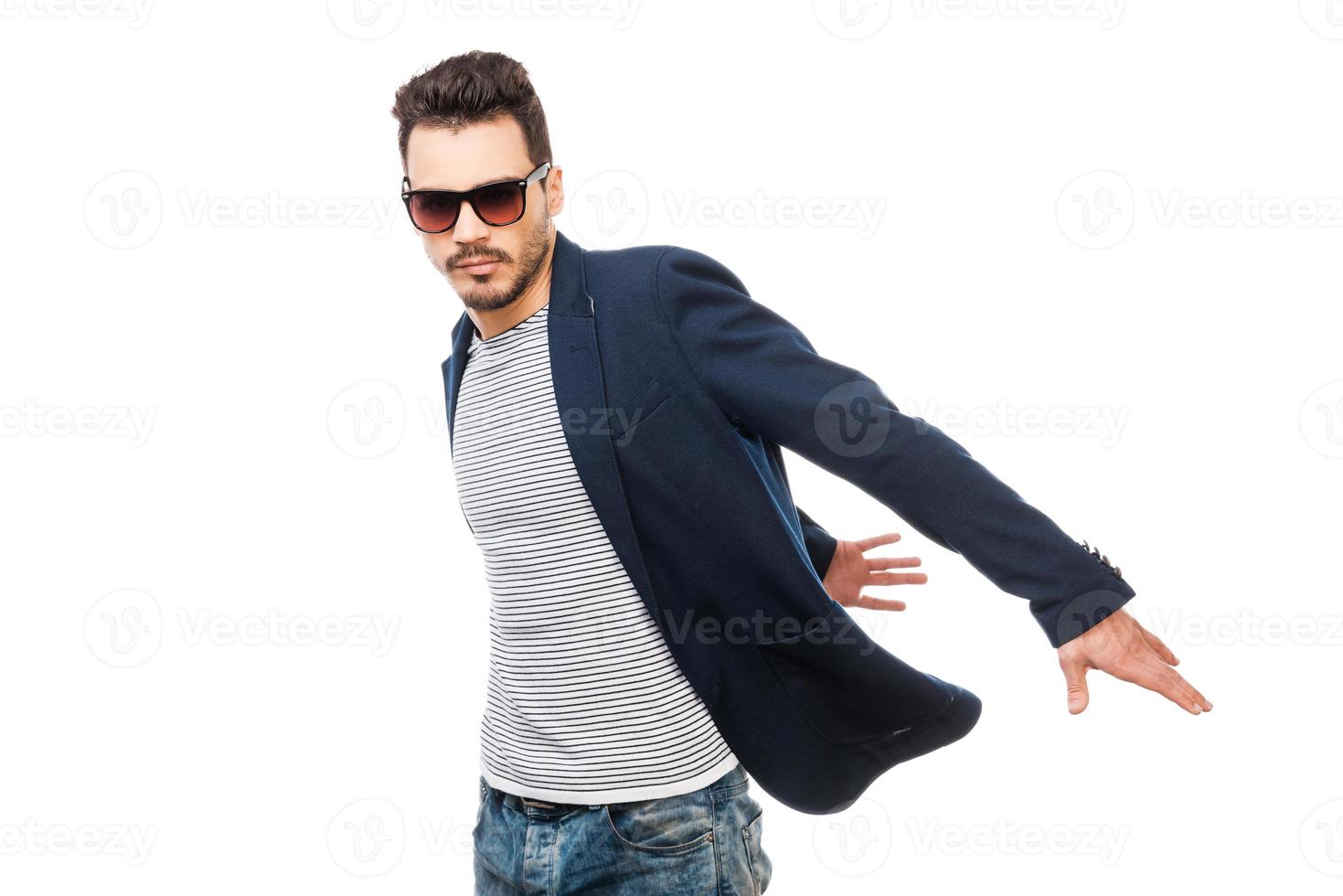 Style in motion. Handsome young man in sunglasses moving against white background photo