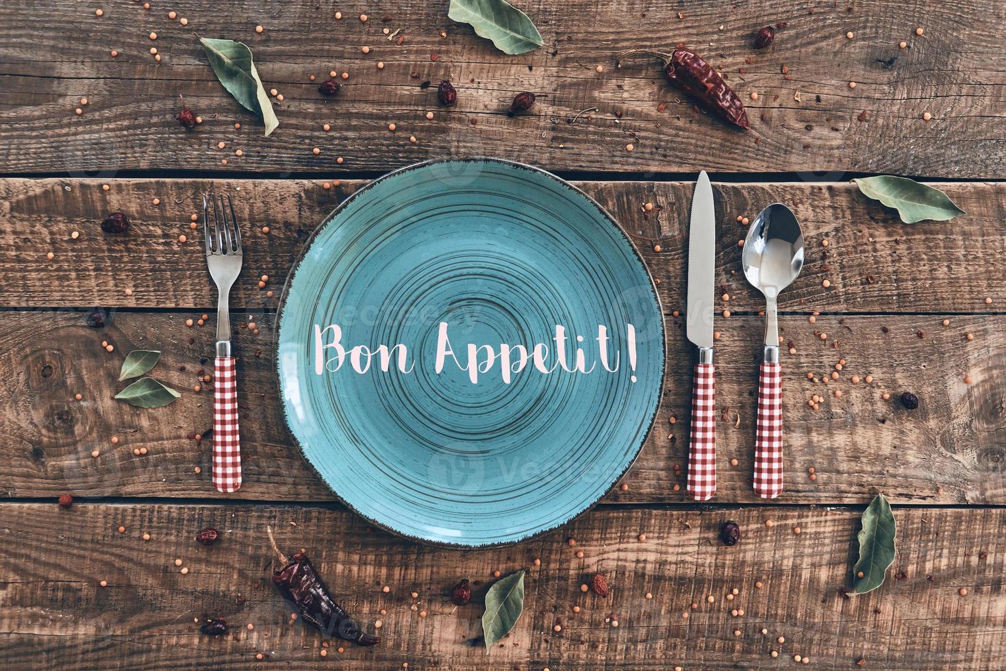 Dinner time. High angle shot of empty plate, fork, spoon, knife lying on rustic table photo
