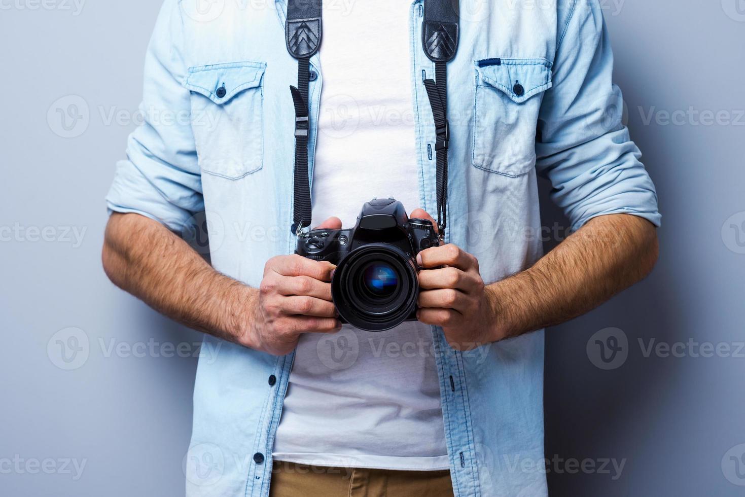 hombre con cámara digital. imagen recortada de un hombre con una cámara digital de pie contra un fondo gris foto