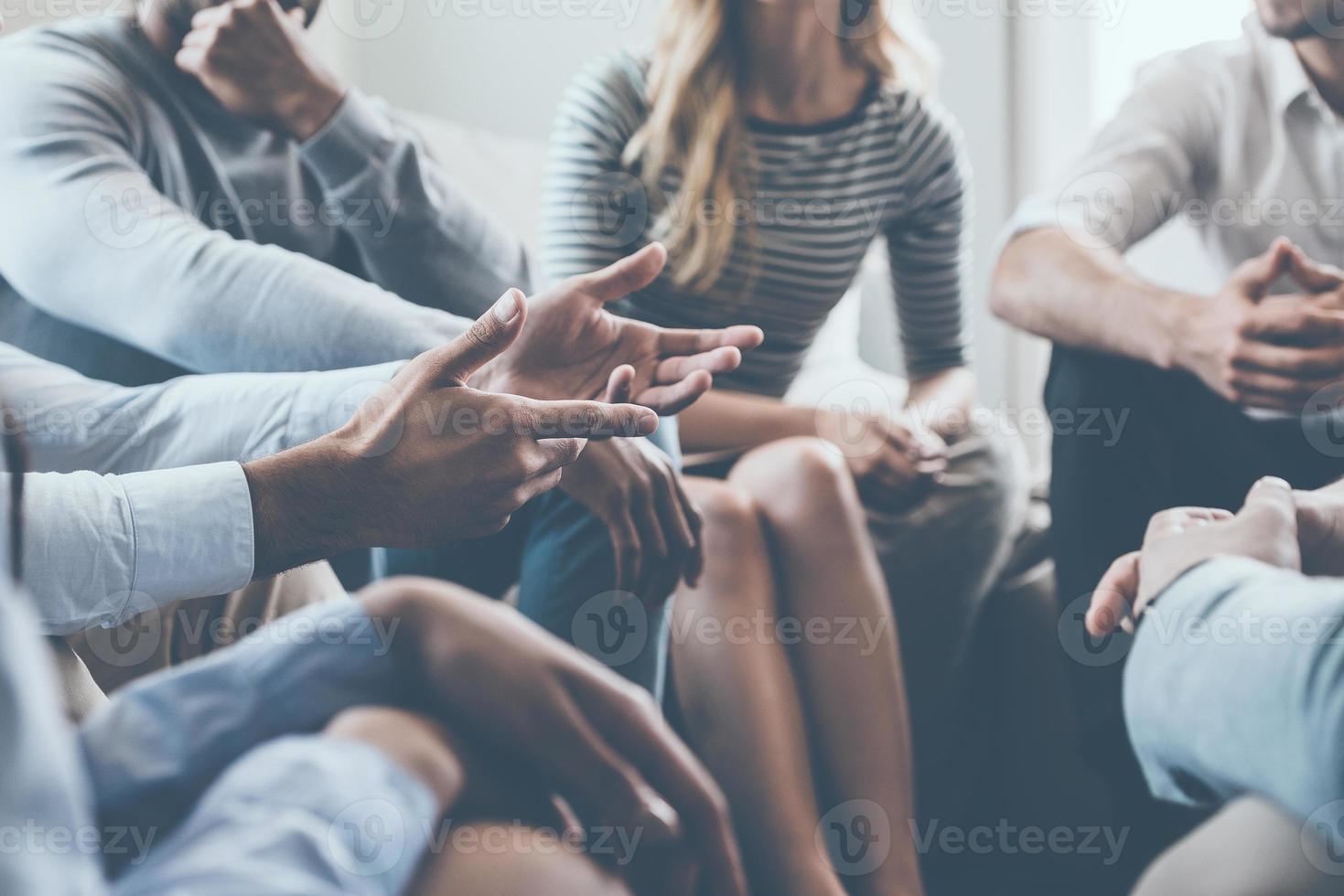 Close-up on discussion. Close-up of people communicating while sitting in circle and gesturing photo