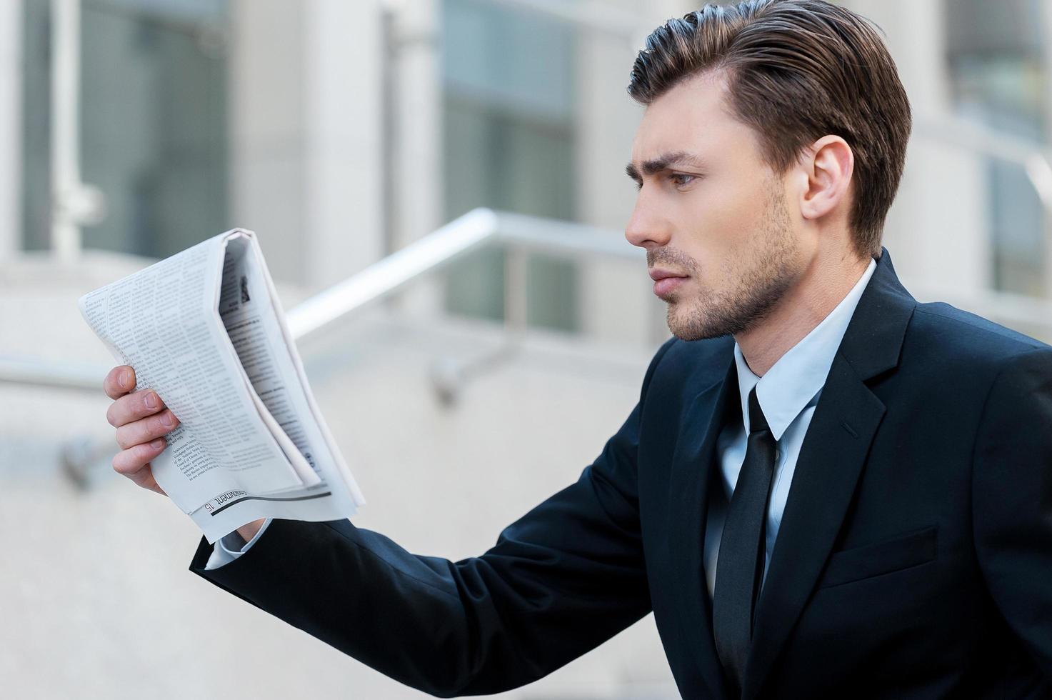 noticias frescas. joven empresario leyendo el periódico foto