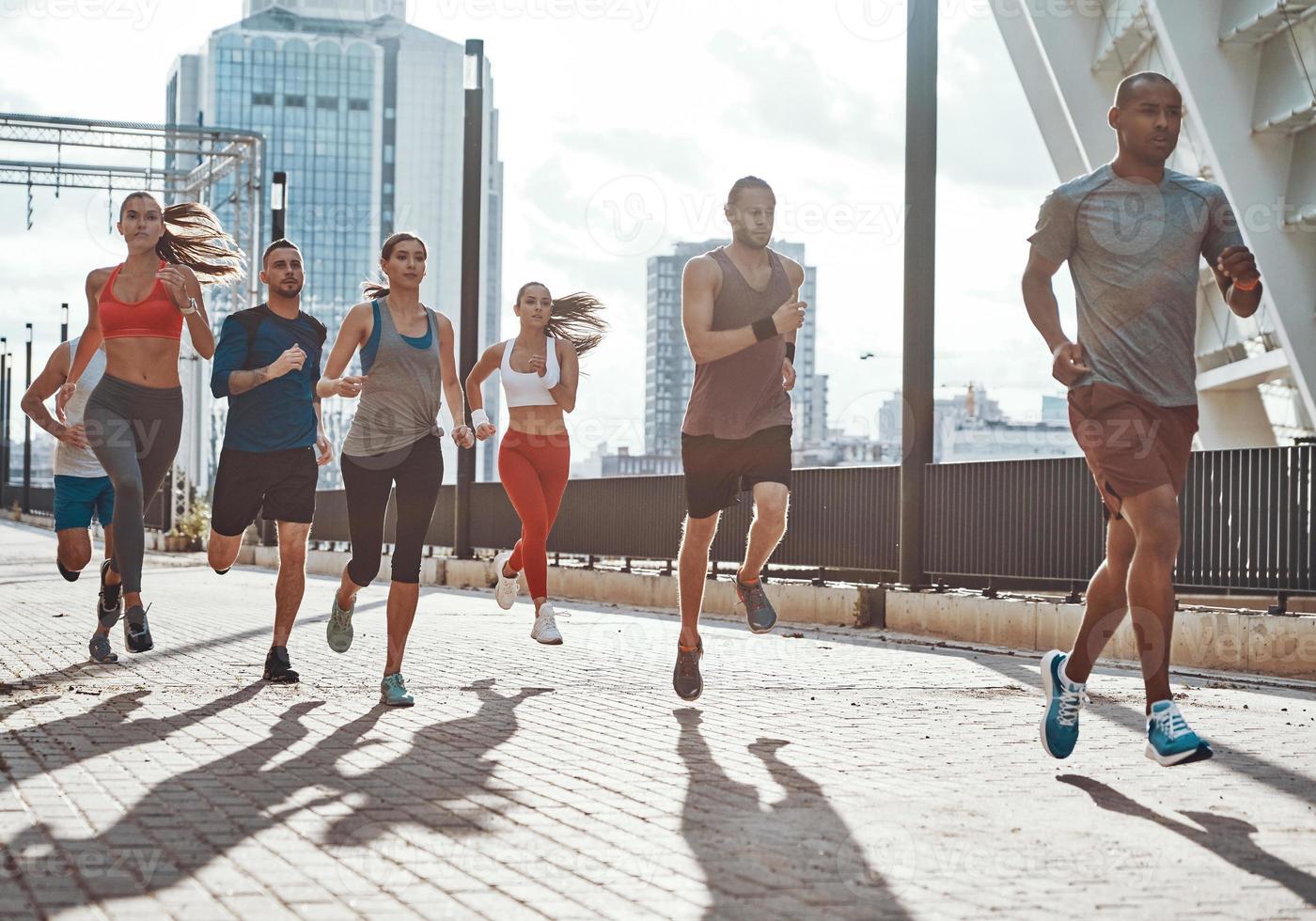 toda la longitud de la gente con ropa deportiva trotando mientras hace ejercicio en la acera al aire libre foto