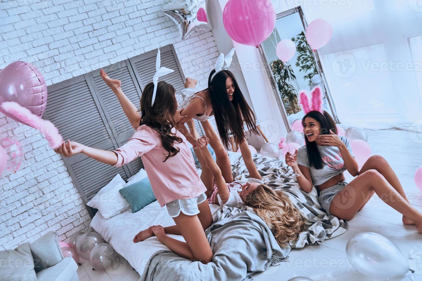 No rules for them. Playful young women in bunny ears having fun and smiling while enjoying home party photo