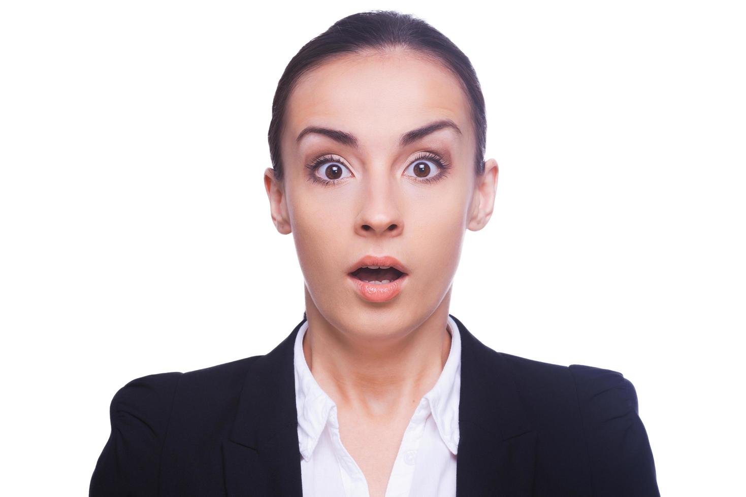 Shocked businesswoman. Surprised young woman in formalwear looking at camera and keeping mouth open while standing isolated on white photo