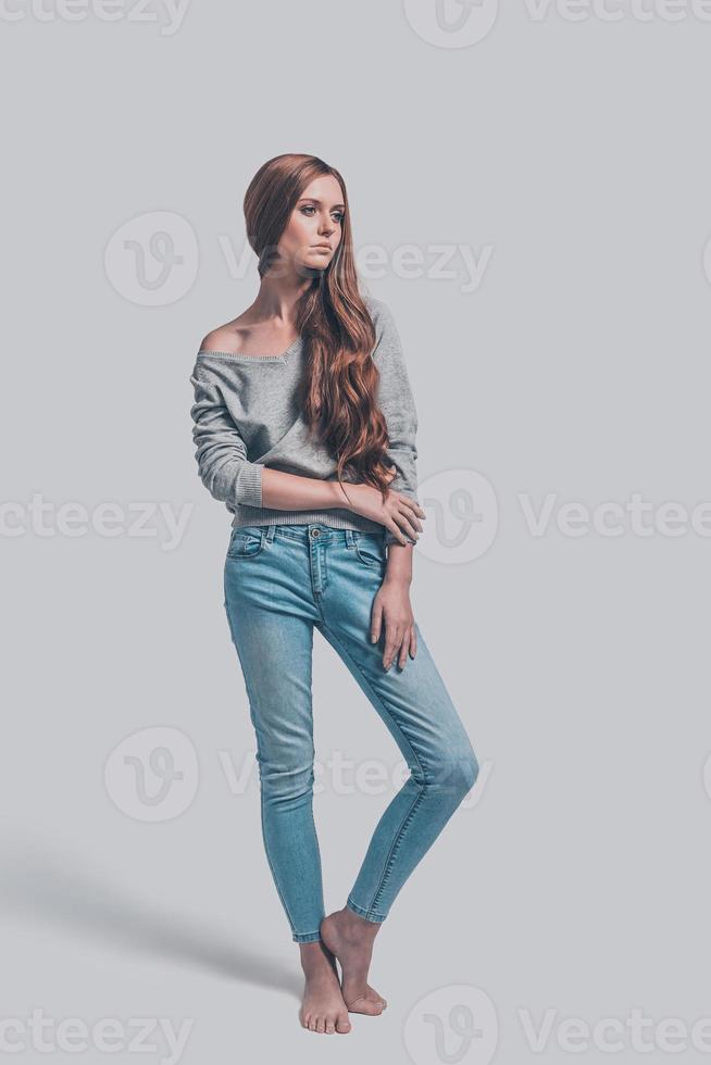 Casual beauty. Full length of attractive young woman in casual wear posing against grey background photo