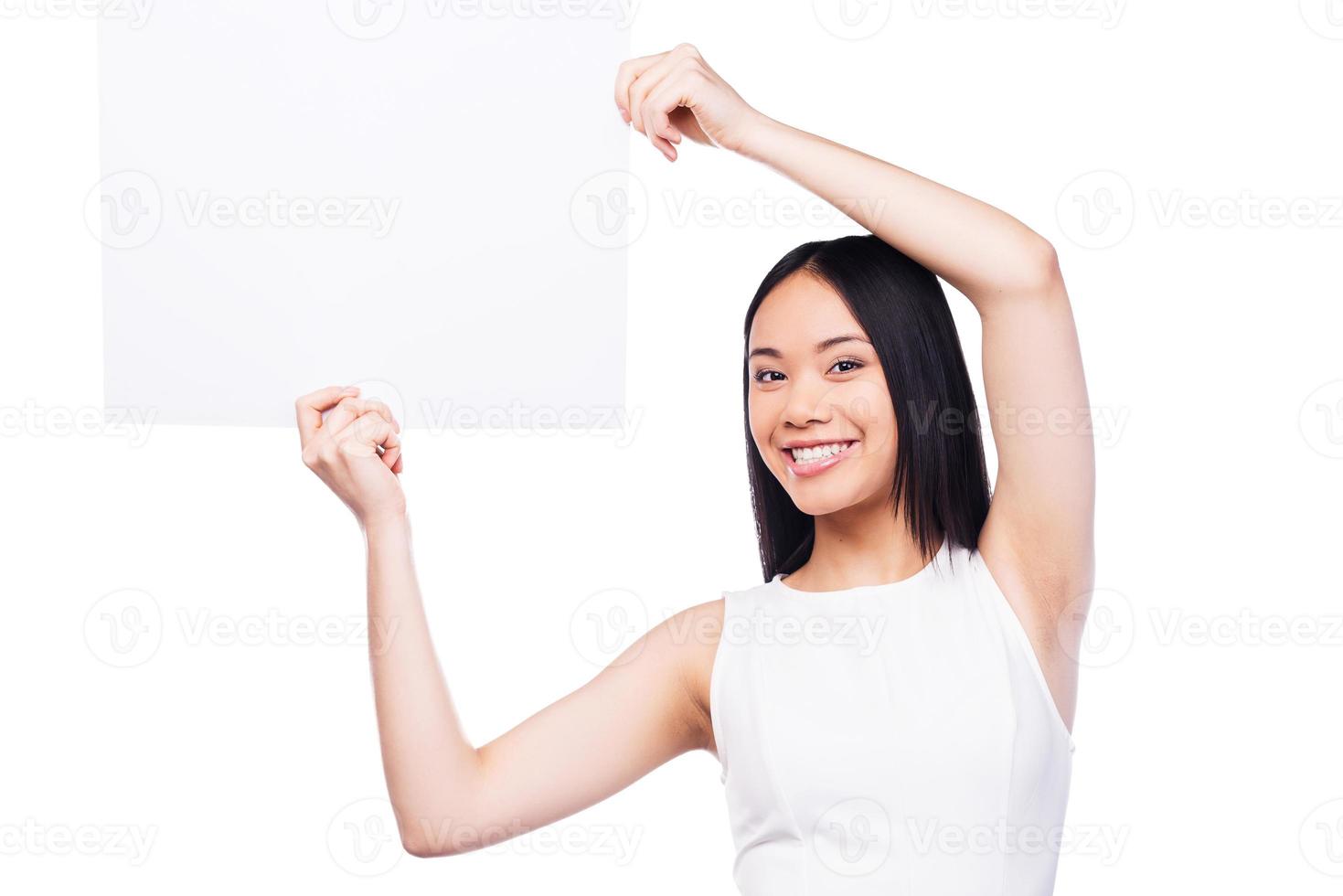 Copy space in her hands. Beautiful young Asian woman holding copy space and smiling while standing against white background photo