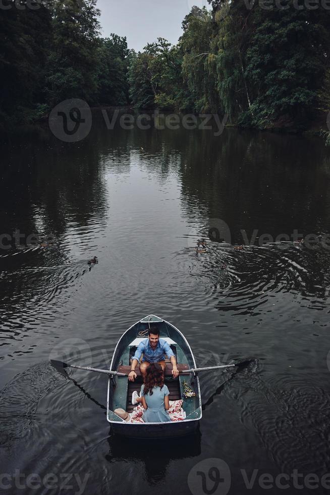 explorando el mundo juntos. vista superior de una hermosa pareja joven que disfruta de una cita romántica mientras rema en un bote foto