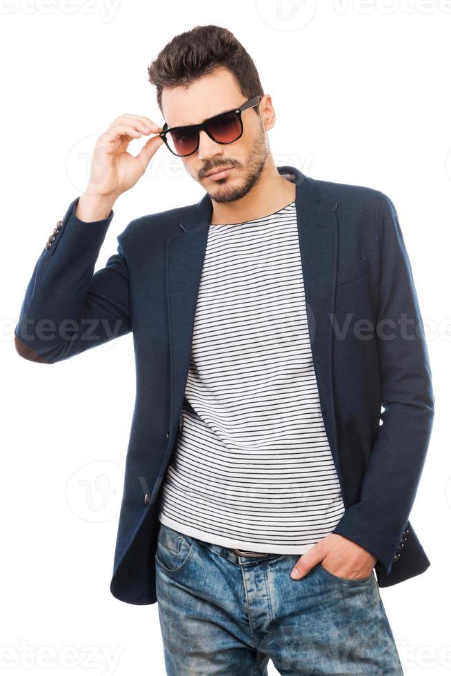 Confident in his style. Handsome young man adjusting his sunglasses while standing against white background photo