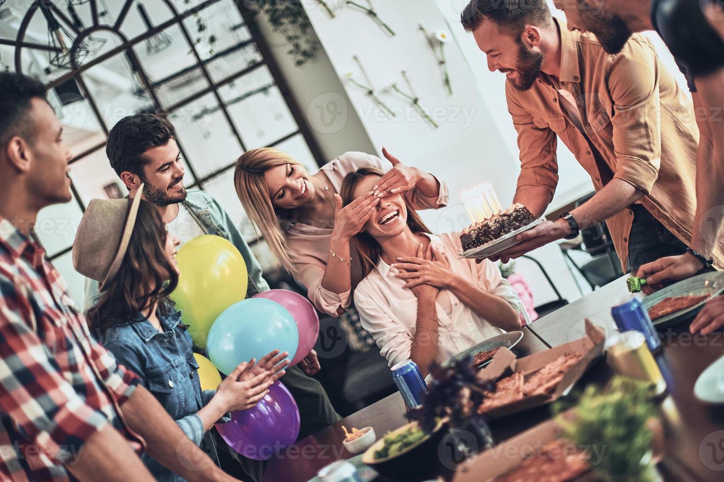 Top view of young people in casual wear gesturing and smiling while having a dinner party indoors photo