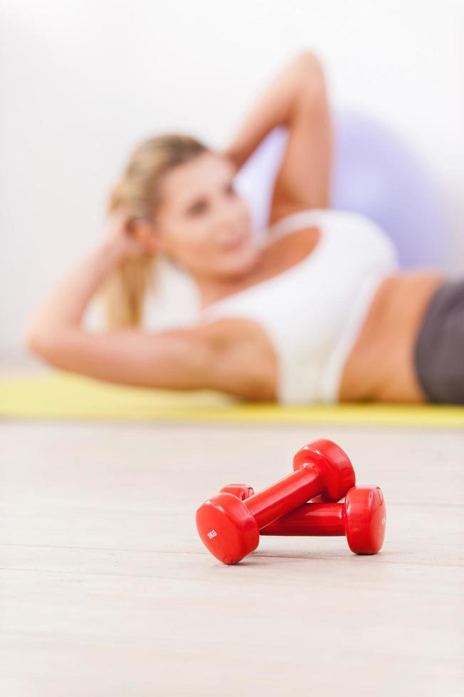 entrenando sus abdominales. mujer madura haciendo ejercicio en la alfombra con pesas en primer plano foto