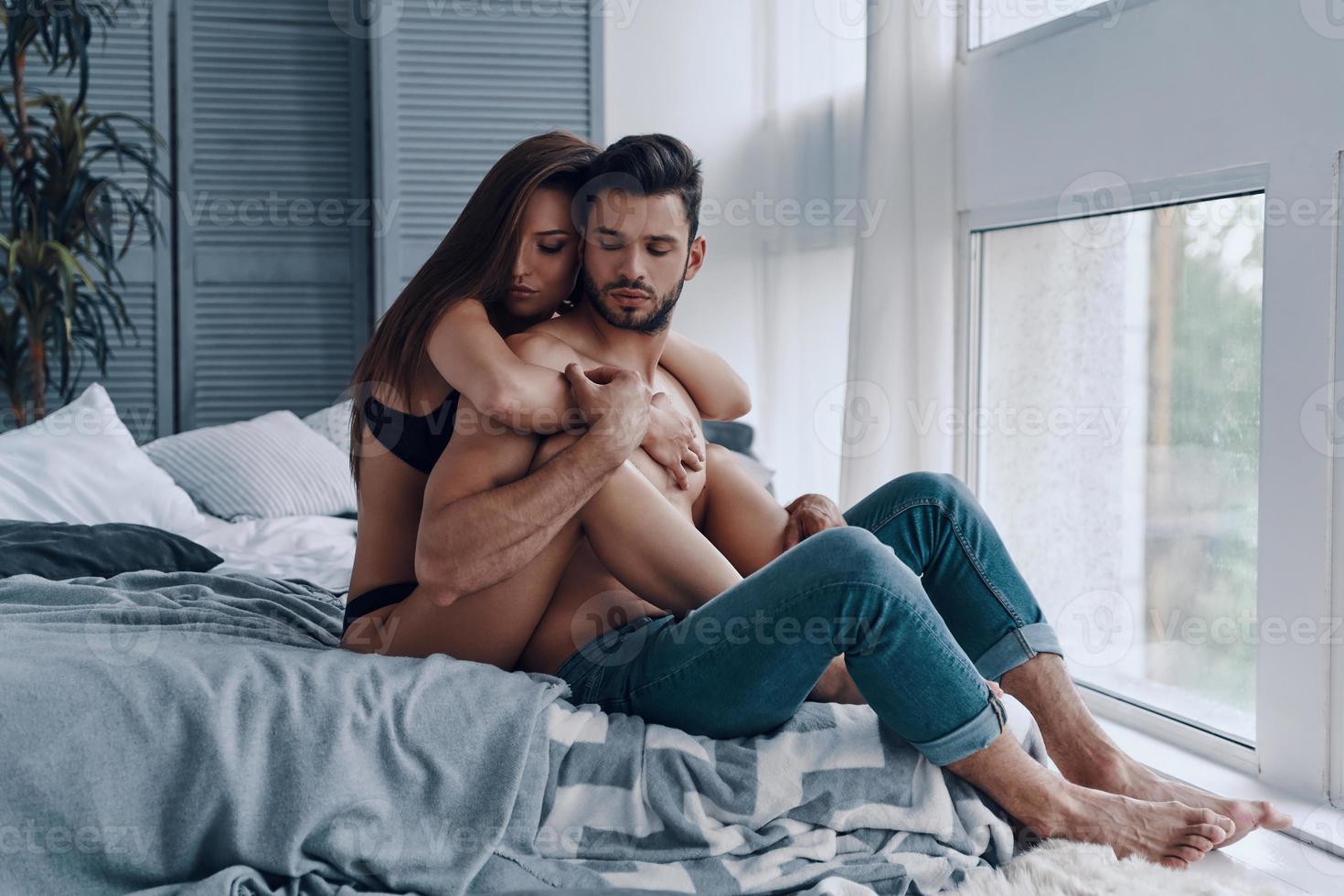 momentos de alegría. hermosa joven pareja semi-vestida abrazándose mientras pasa tiempo en el dormitorio foto