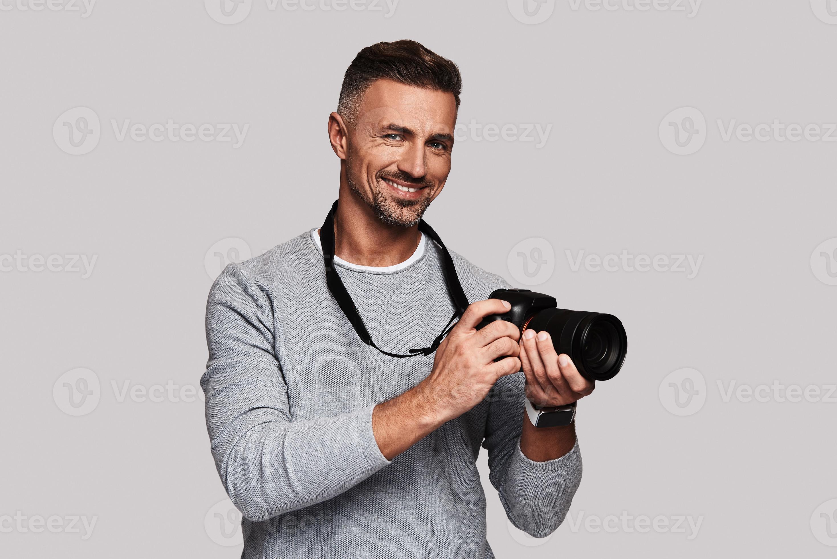 His best hobby. Good looking young man holding digital camera and