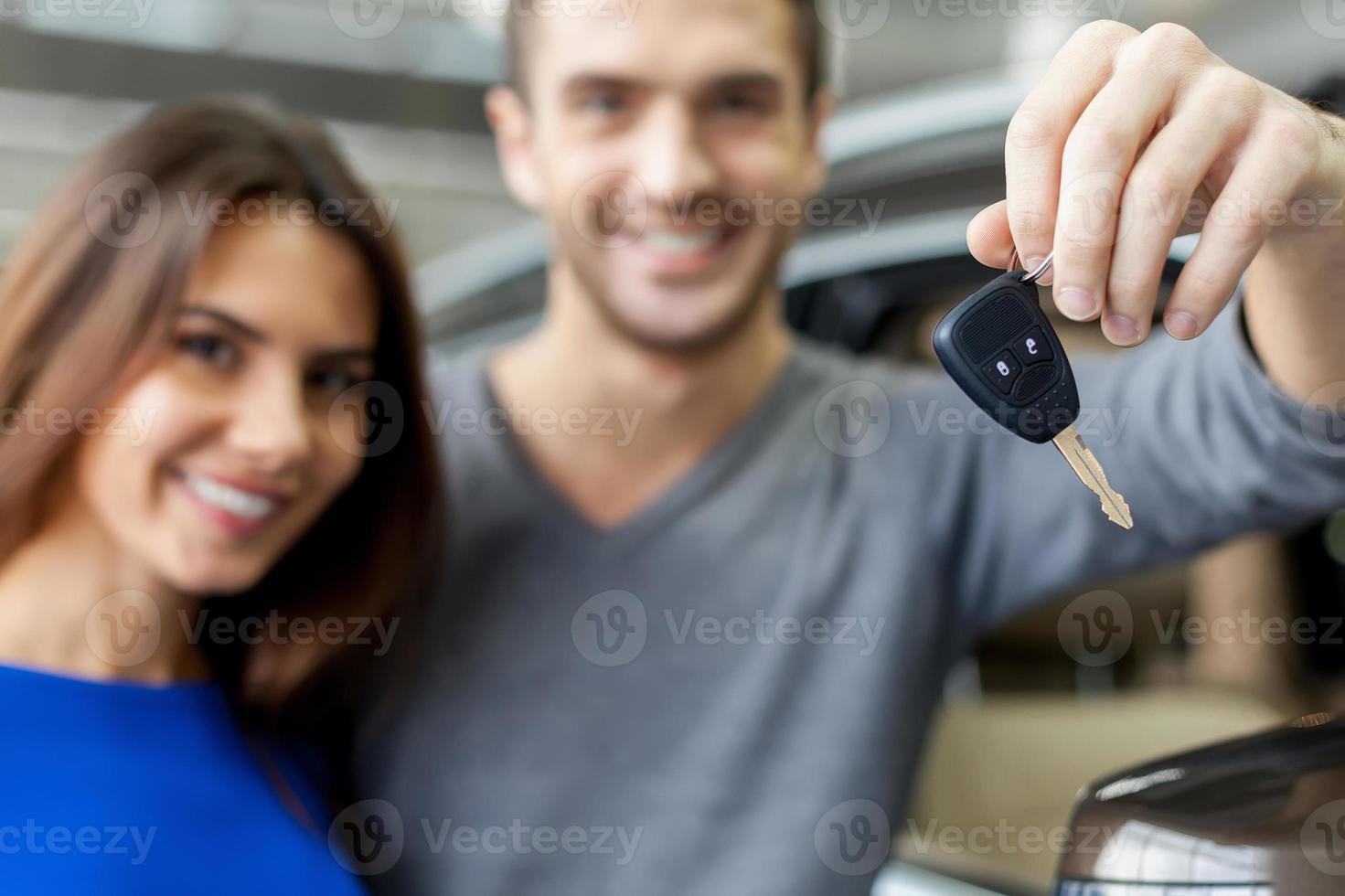 Key from a new car. Young couple standing near then new car and holding a key photo