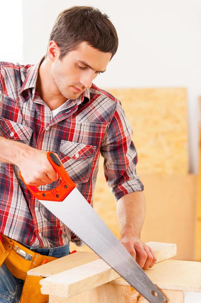 Handyman using saw. Young handyman using saw in workshop photo