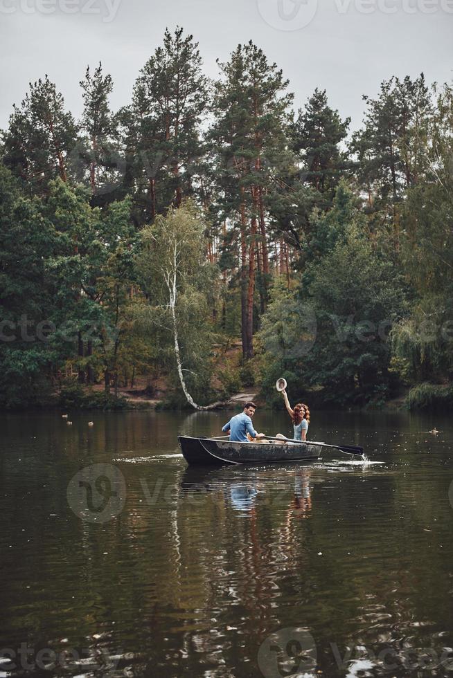 disfrutando el tiempo juntos. hermosa pareja joven disfrutando de una cita romántica y sonriendo mientras rema un bote foto