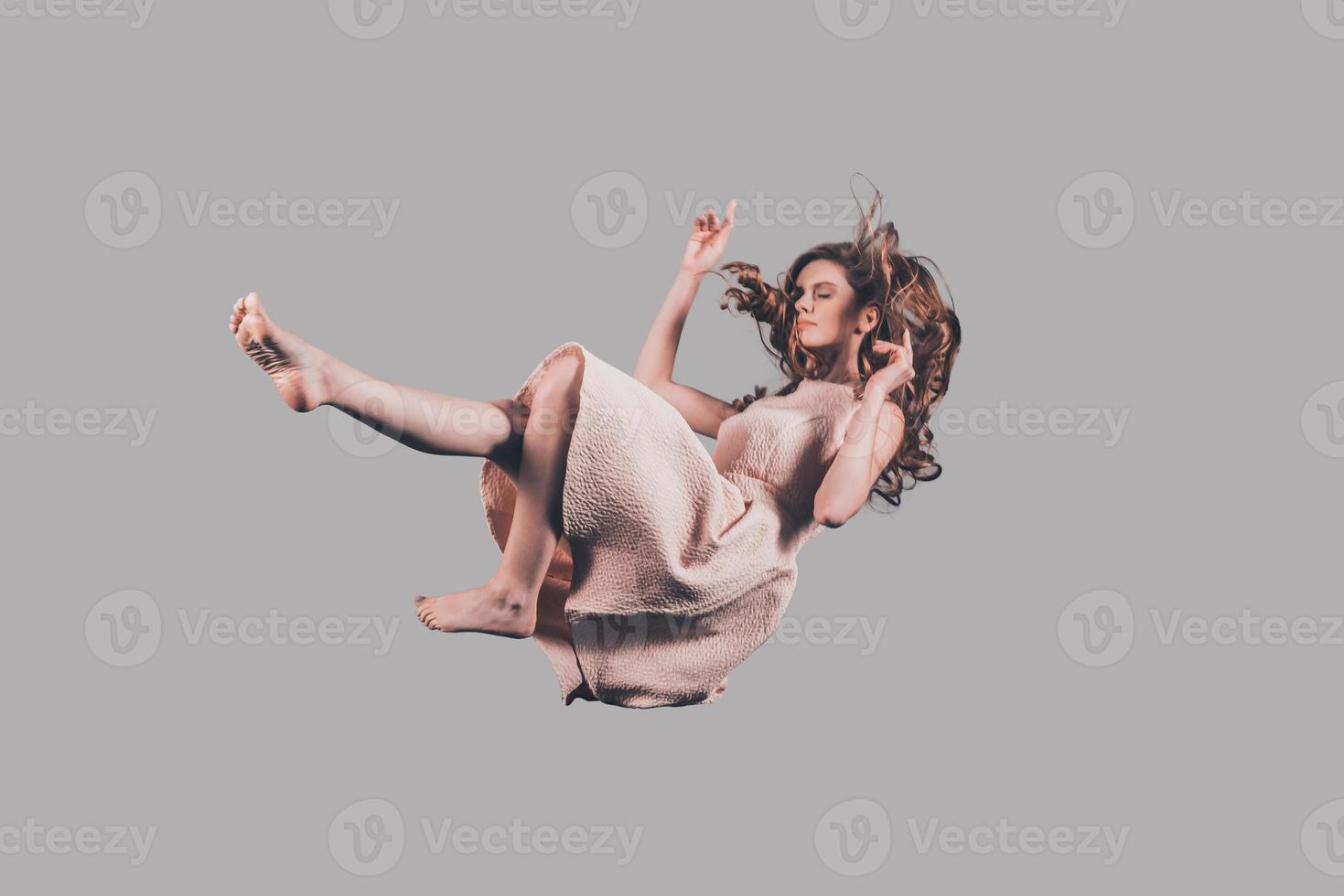 Falling to somewhere. Studio shot of attractive young woman hovering in air photo