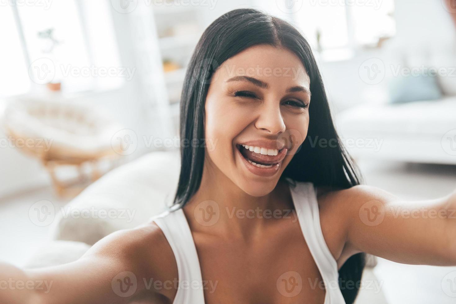 Having fun at home. Self portrait of young beautiful woman looking at camera and smiling while sitting on the couch at home photo