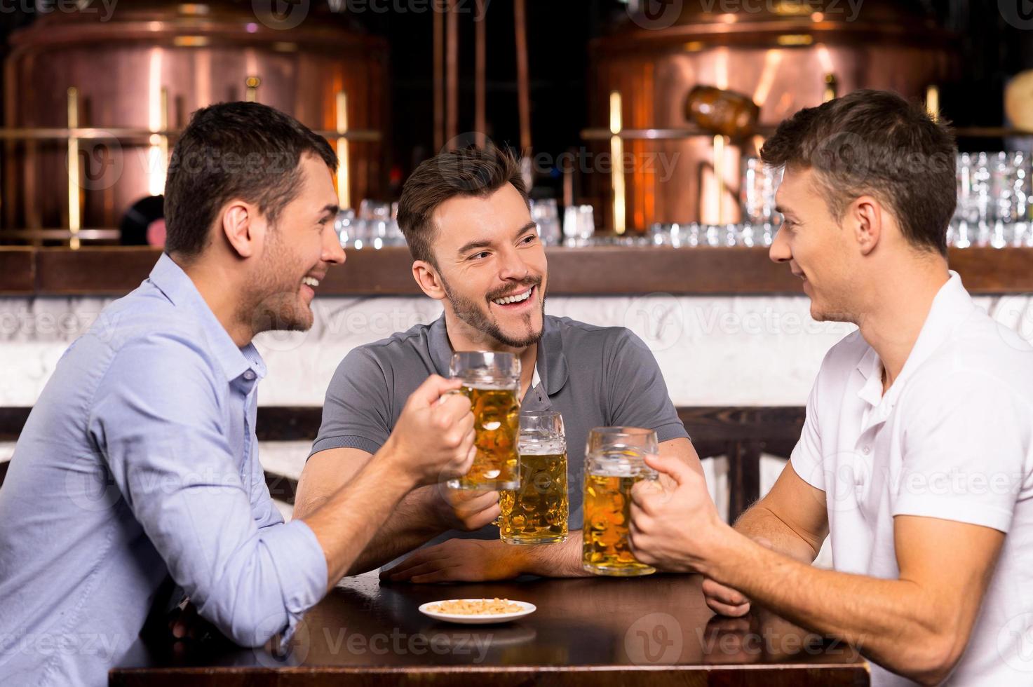 pasar tiempo en el bar. tres alegres amigos bebiendo cerveza en el bar foto