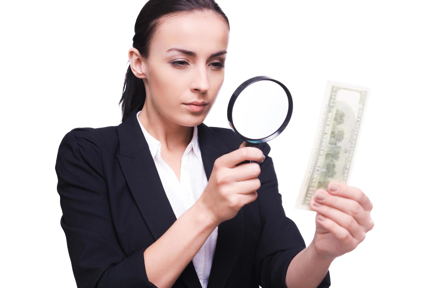 Finance inspector. Confident businesswoman looking through magnifying glass at one hundred dollar bill photo