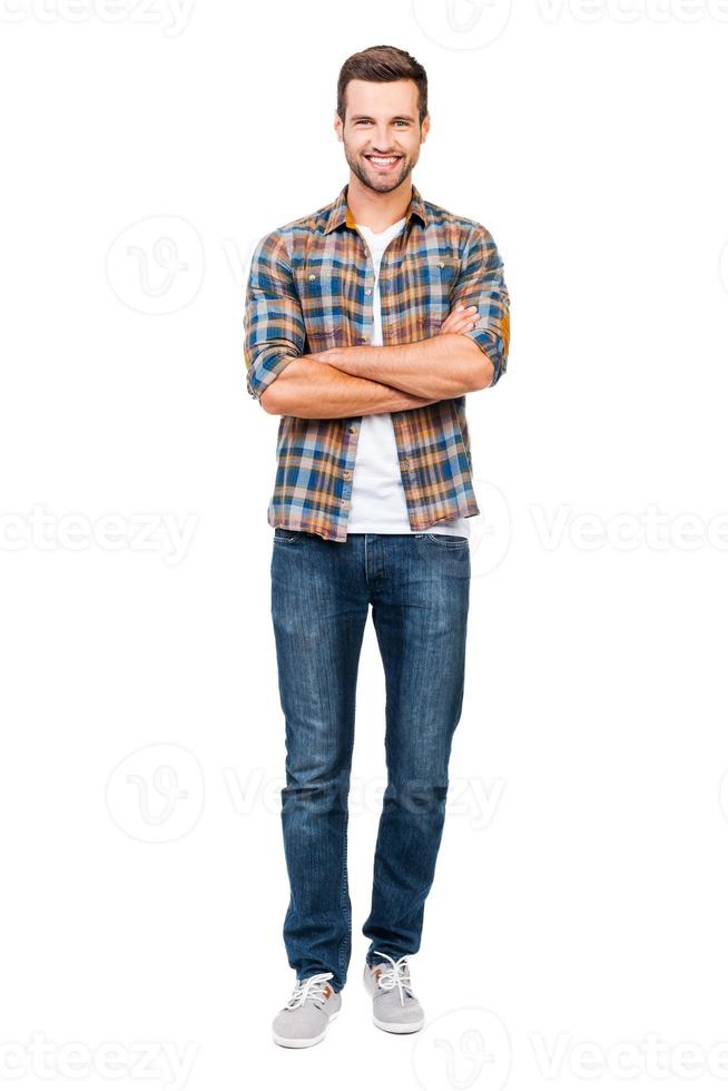 Reliable guy. Full length of smiling young man keeping arms crossed and looking at camera while standing against white background photo