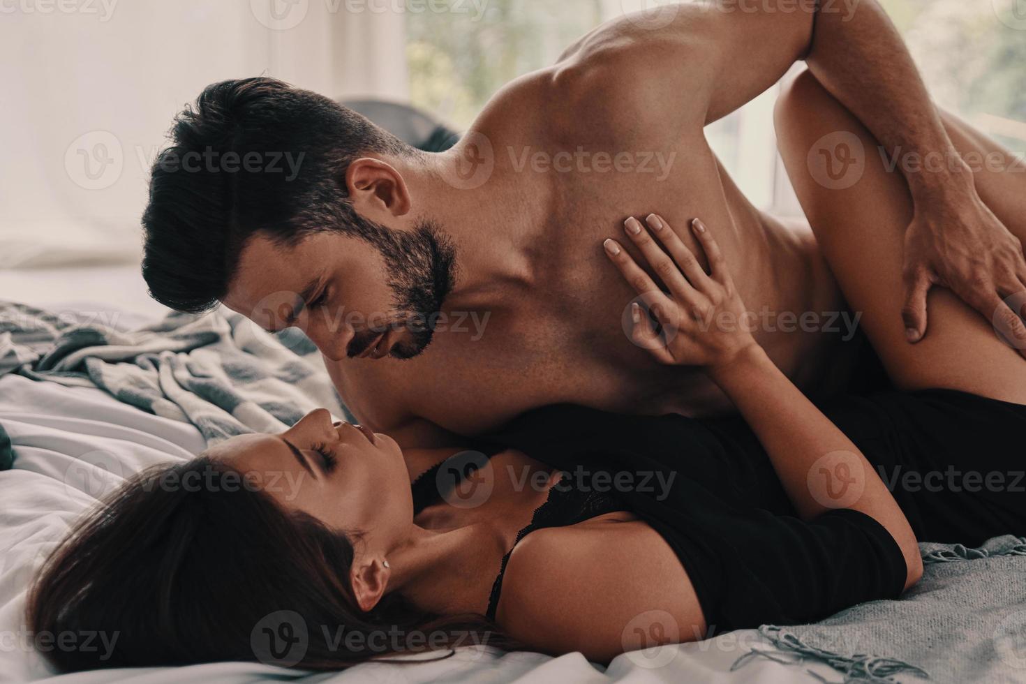 Pure passion. Beautiful young couple touching each other while lying in bed together photo