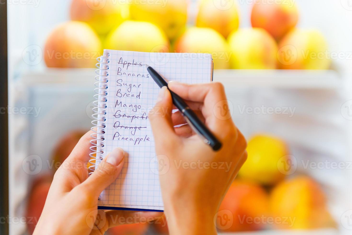 comprobando la lista de compras. primer plano de mujer revisando la lista de compras con manzanas en el fondo foto