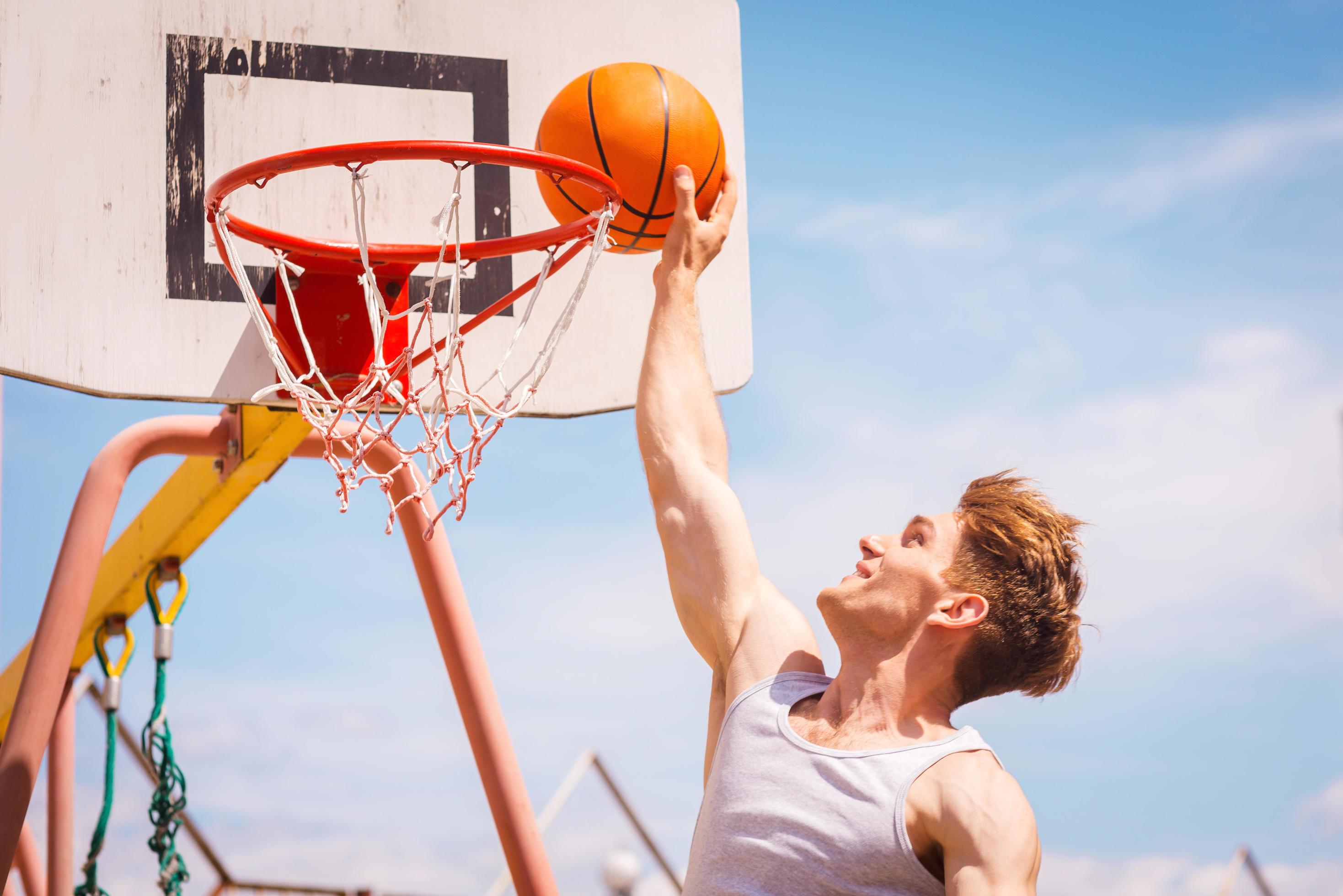 Slam Dunk. Side view of young basketball player making slam dunk