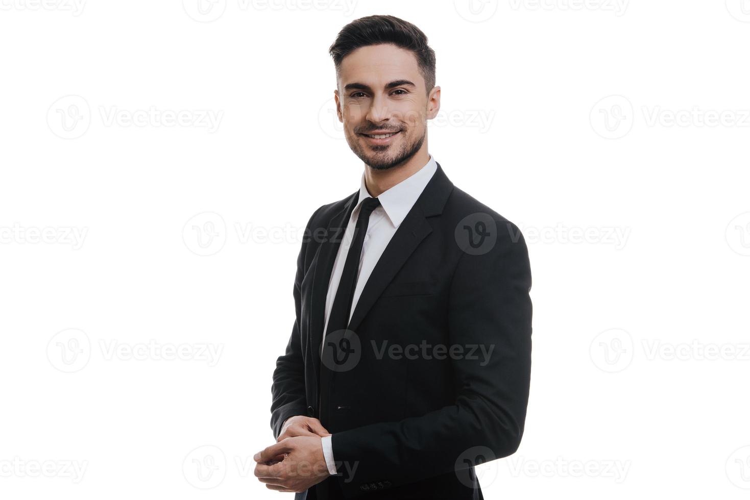 Young and successful. Handsome young man in full suit adjusting his sleeve and looking at camera while standing against white background photo