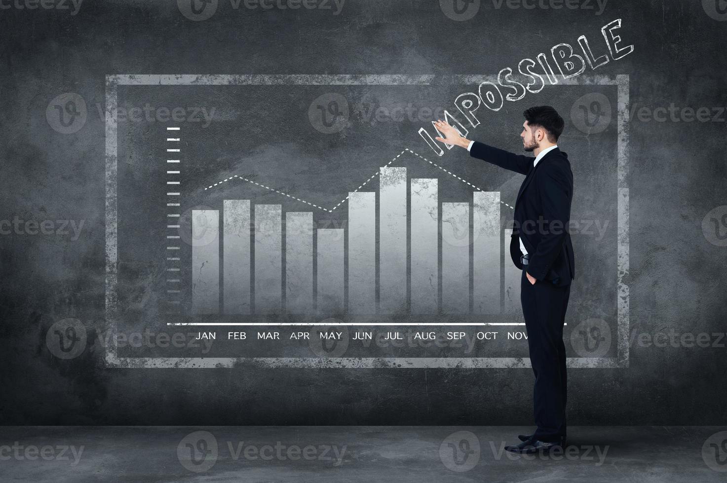 Everything is possible. Full length of confident young man in full suit standing near concrete wall and touching illustrated chart photo