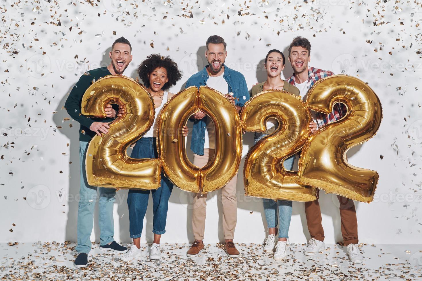 Group of young beautiful people in casual clothing carrying gold colored numbers  and smiling photo