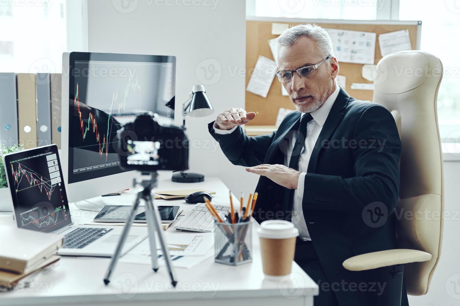 Senior man in elegant business suit using modern technologies while making social media video photo
