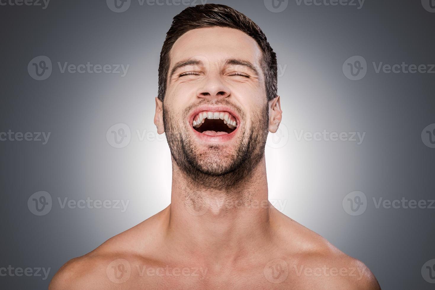 True happiness. Portrait of handsome young shirtless man keeping eyes closed and smiling while standing against grey background photo