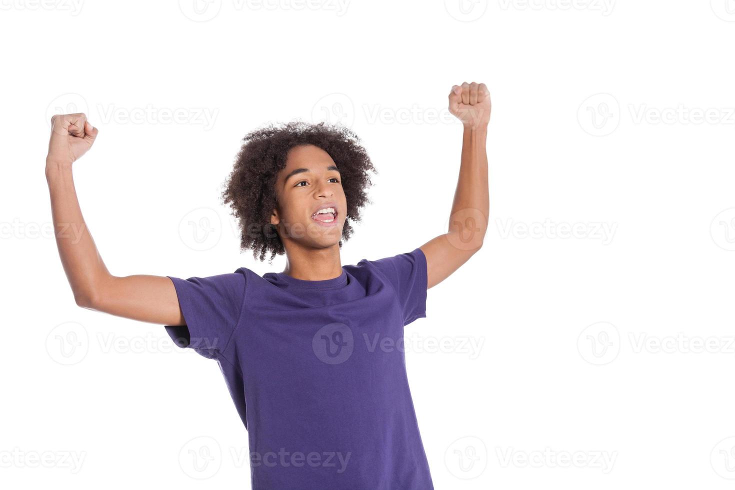 I am a winner Happy African teenage boy keeping arms raised while standing isolated on white photo