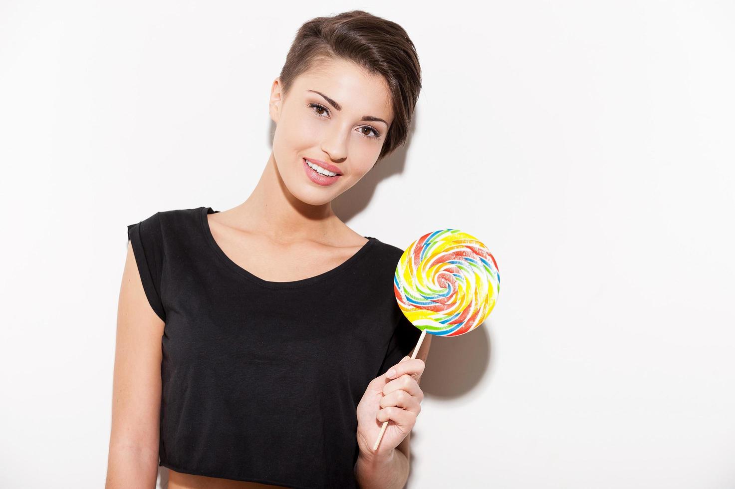 Candy girl. Attractive young short hair woman holding a big lollipop and smiling photo