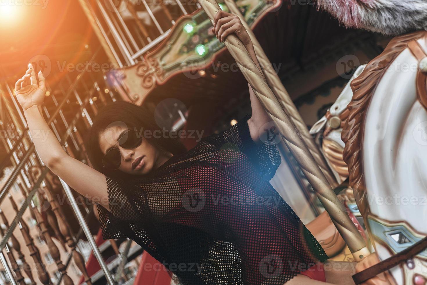 Just like a kid. Attractive young mixed raced woman in red bikini riding merry-go-round photo