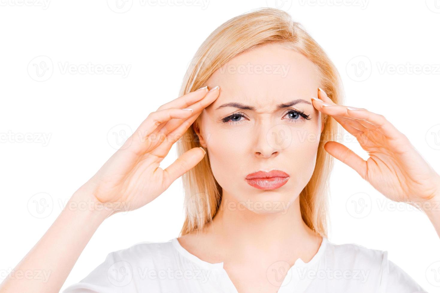 Terrible headache. Depressed mature women touching her cheekbone and looking at camera while standing against white background photo