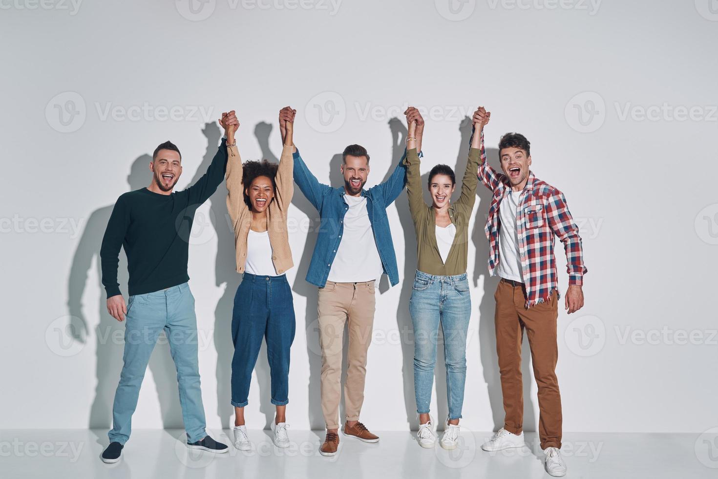 Group of young beautiful people in casual clothing holding hands clasped and smiling photo