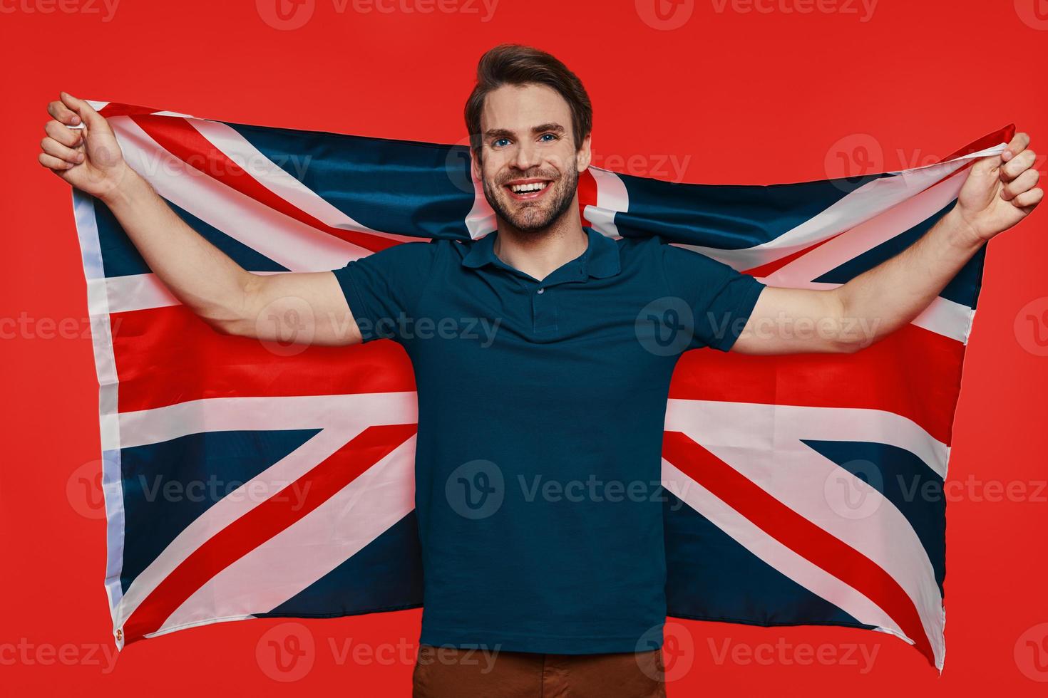 Handsome young man in casual wear carrying British flag and smiling photo