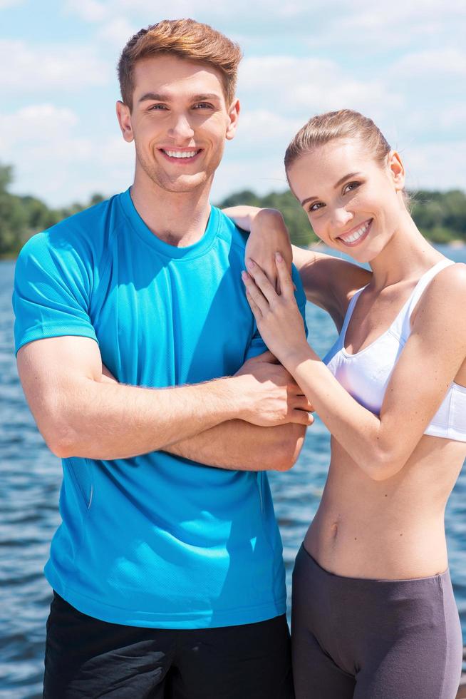 Fitness couple. Beautiful young couple in sports clothing standing together outdoors and smiling photo
