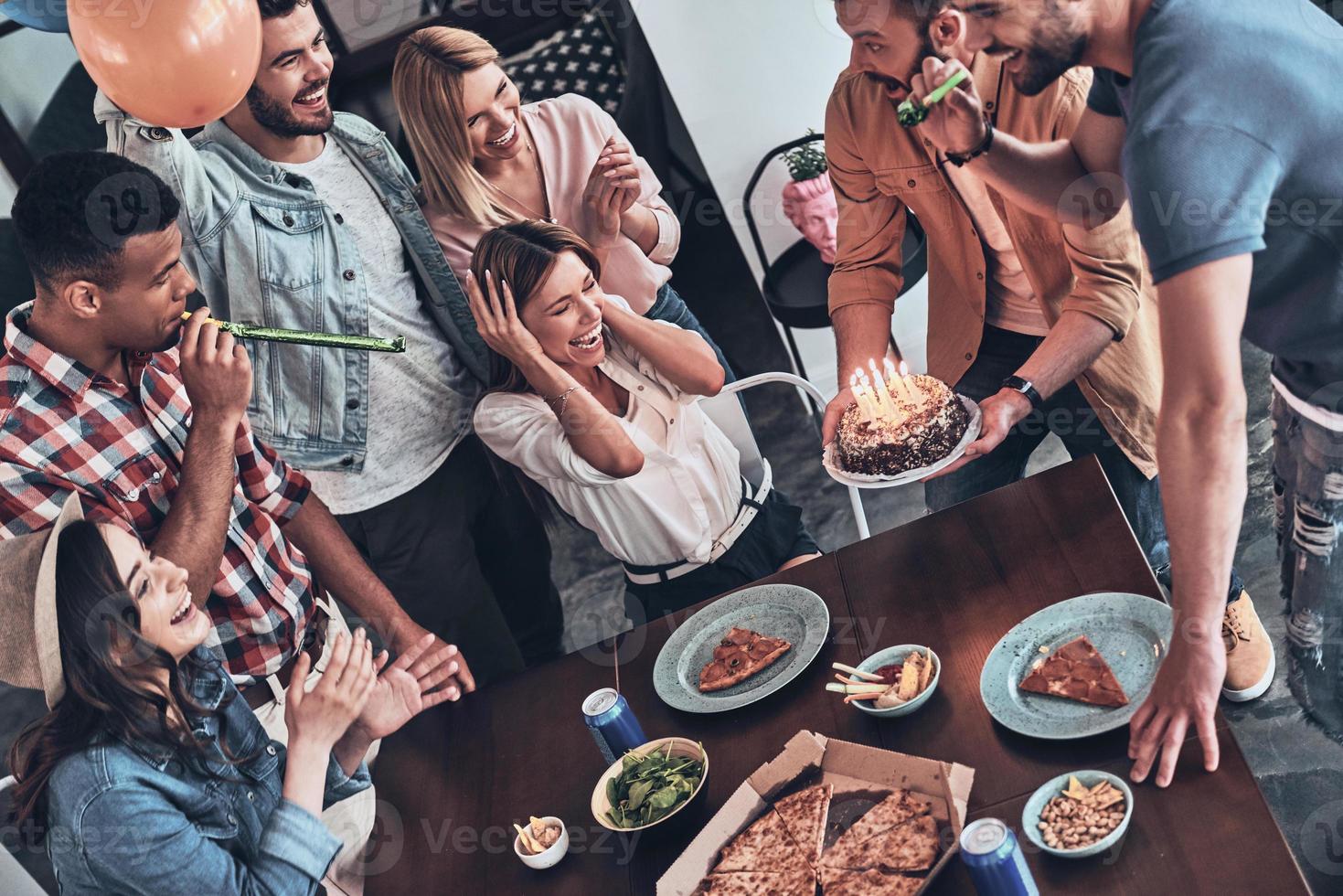 Make a wish Top view of happy people celebrating birthday among friends and smiling while having a dinner party photo