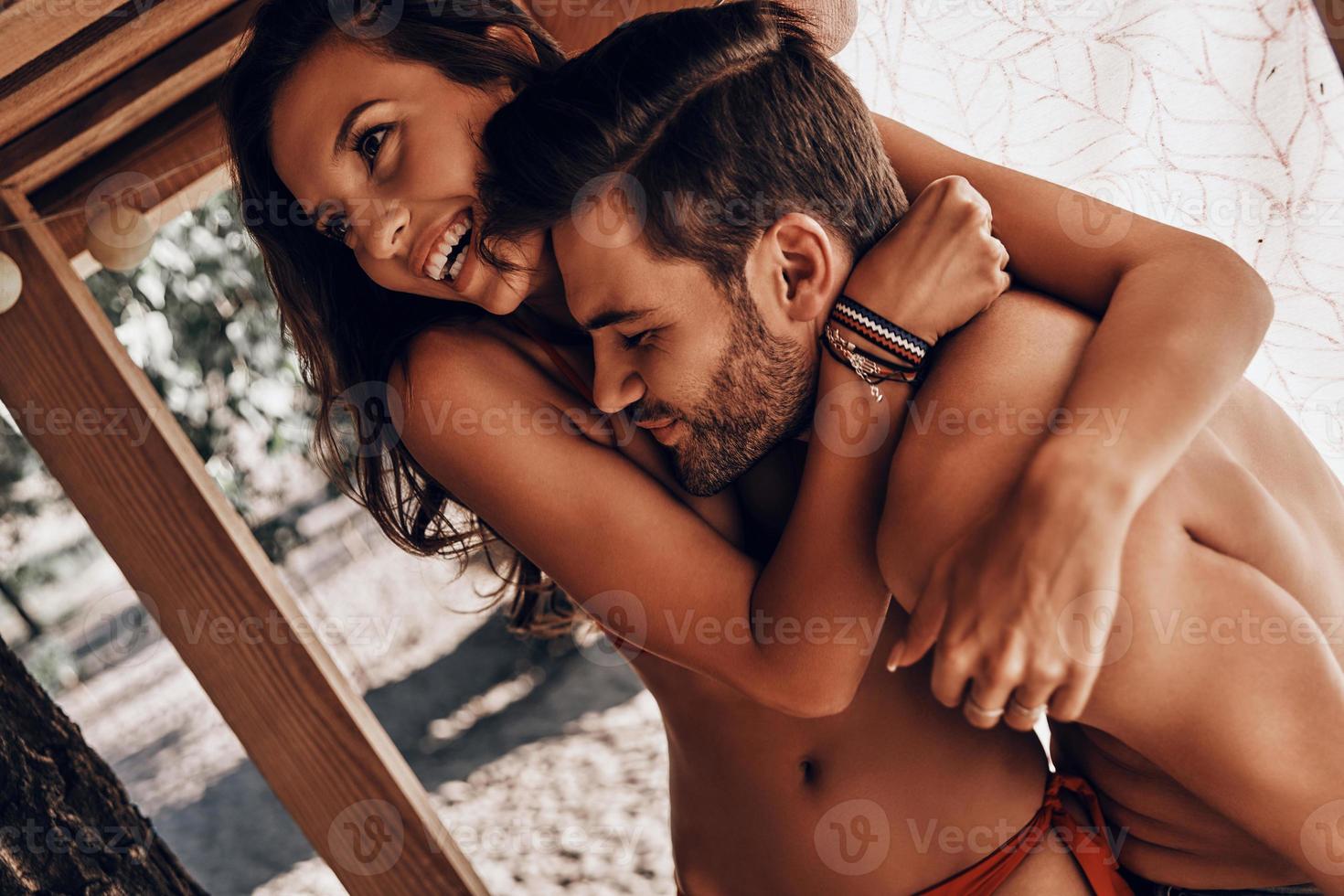hermosa joven pareja abrazándose y sonriendo mientras descansa en la cabaña de la playa foto