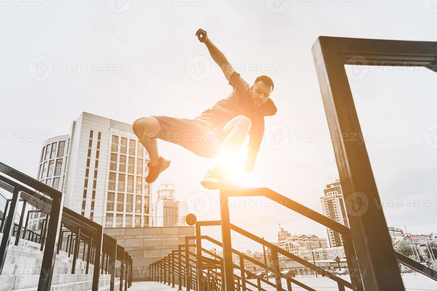 Training to become the best. Low angle view of handsome young man in sport clothing jumping over railing while exercising outside photo