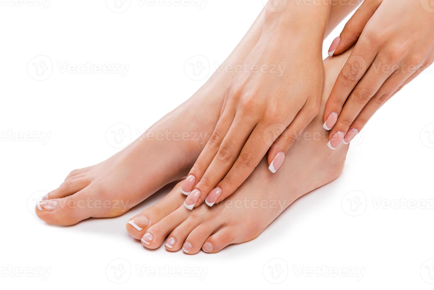 Perfect feet. Cropped picture of a beautiful young woman touching legs while sitting against white background photo