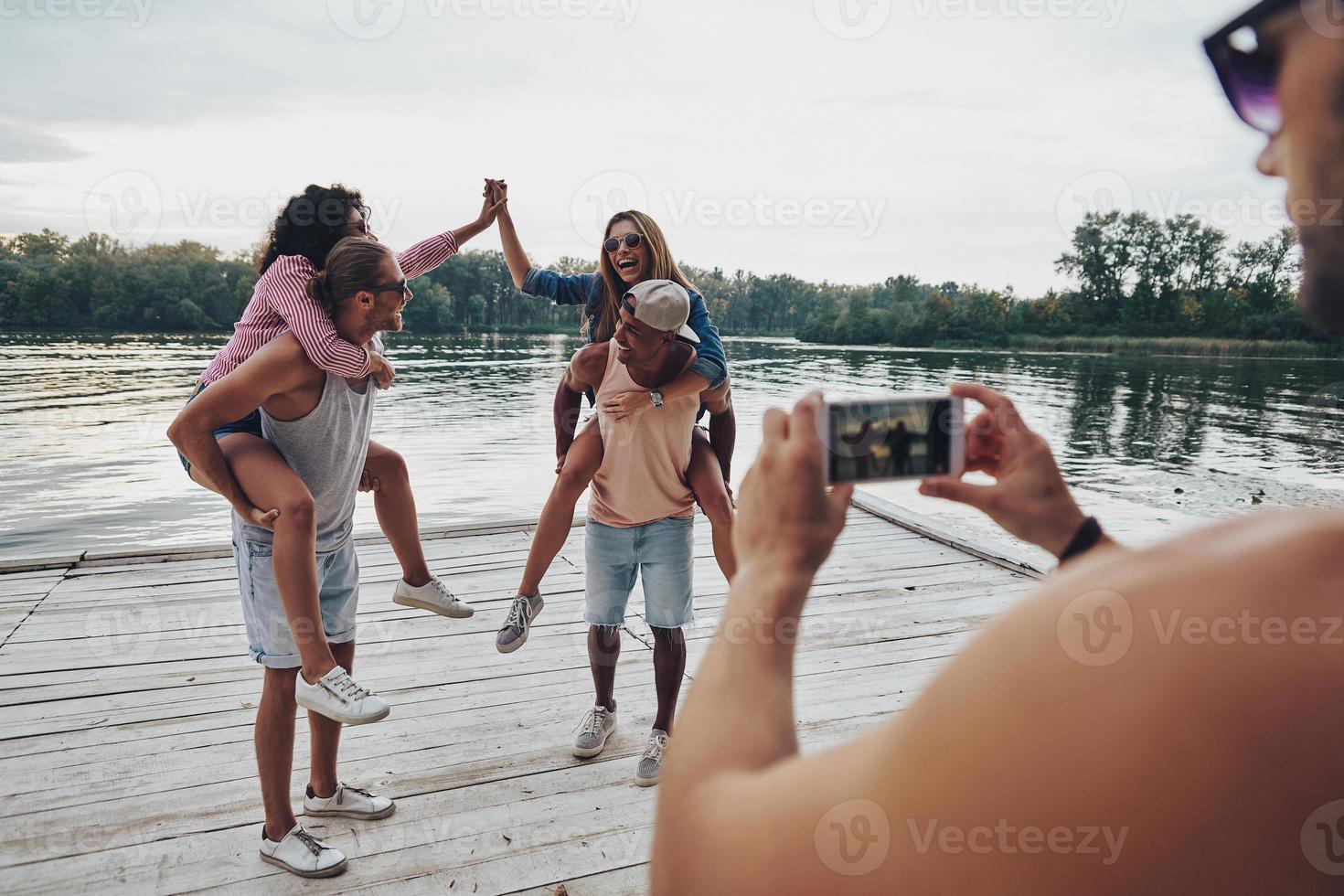 Beautiful young couples spending carefree time while standing on the pier photo