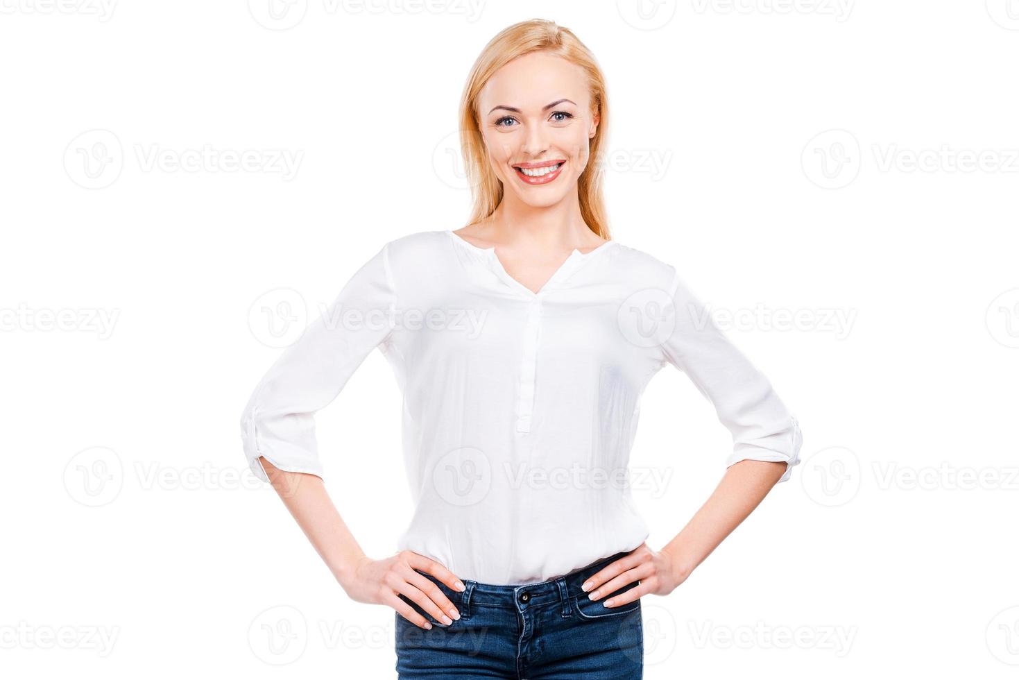 She is really cute. Beautiful mature women looking at camera and smiling while holding hands on hip and standing against white background photo