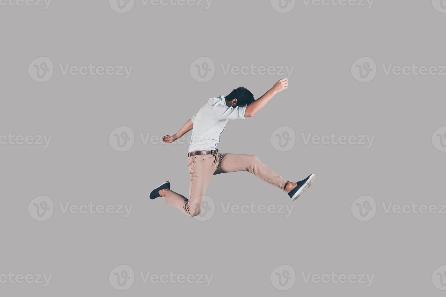 Keep moving Mid-air shot of handsome young man jumping and gesturing against background photo